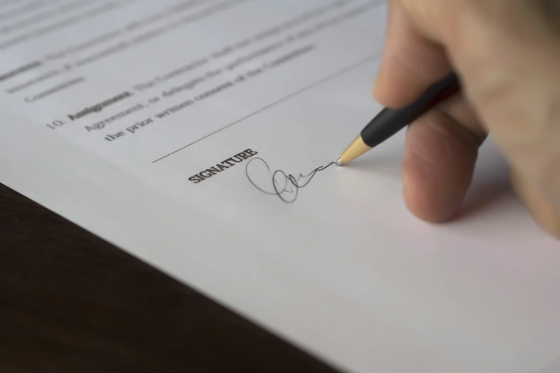 A person signing a company registration contract at a desk