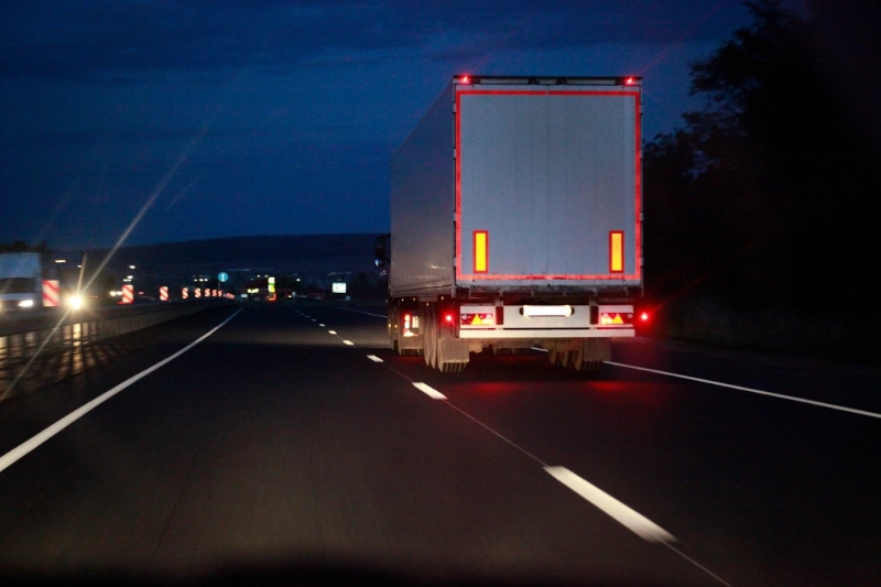 An articulated freight lorry on a highway at dusk