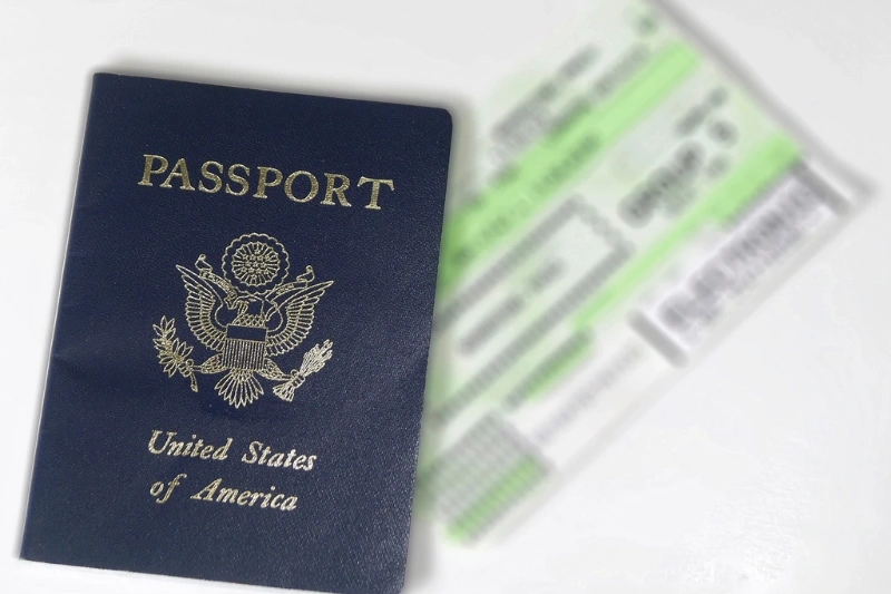 A passport resting on a boarding pass and travel papers